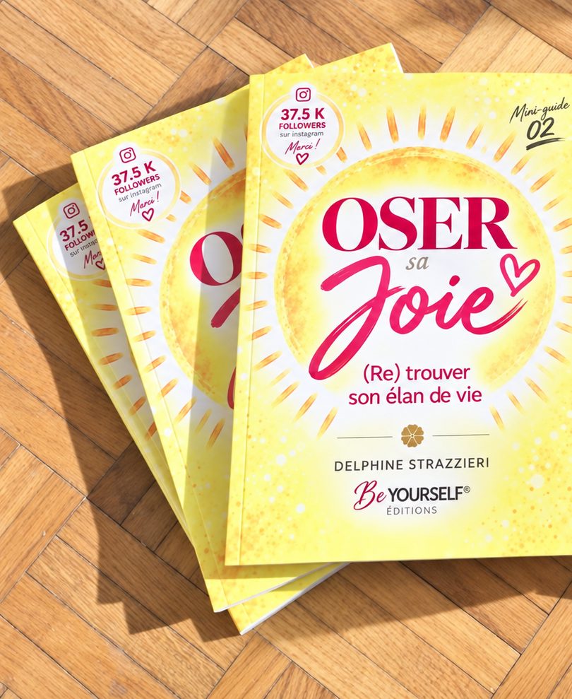 Plusieurs exemplaires imprimés d’OSER sa JOIE posés sur un parquet ensoleillé